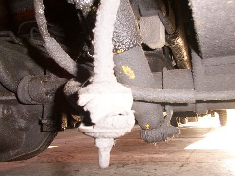 1988 Ford C-350 (Centurion Conversions) - Close-up of a suspension part, likely a sway bar link, covered in a white substance.