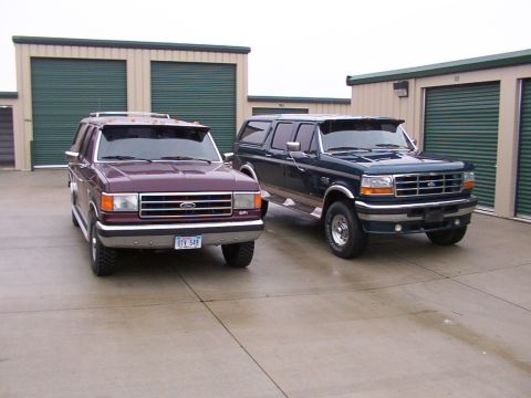1988 Ford C-350 (Centurion Conversions) - Two Ford Bronco Centurion Conversions are parked in front of storage units, one maroon and one dark blue.