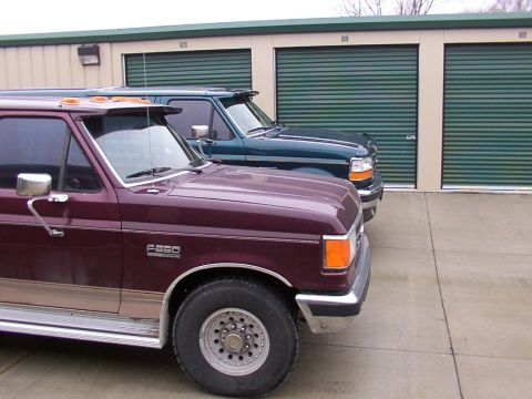 1988 Ford C-350 (Centurion Conversions) - Two Ford trucks are parked in front of storage units.