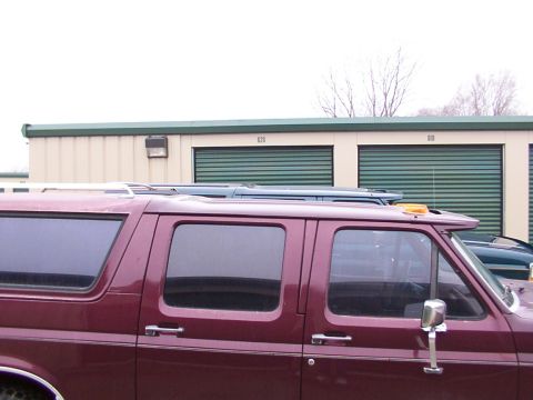 1988 Ford C-350 (Centurion Conversions) - Side view of a maroon van and a blue SUV parked outdoors.