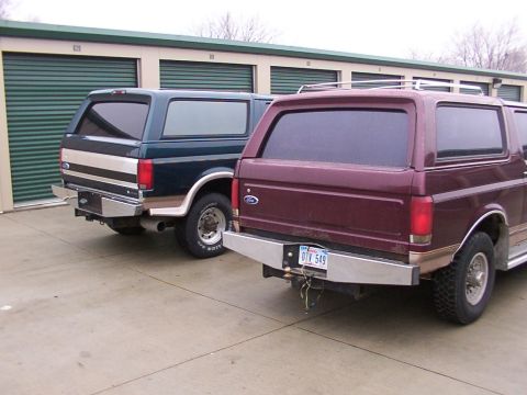 1988 Ford C-350 (Centurion Conversions) - Two Ford Broncos parked in front of storage units, one maroon and one dark blue.