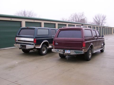 1988 Ford C-350 (Centurion Conversions) - Two Ford SUVs, one maroon and one dark blue, are parked in front of storage units.