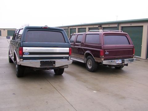 1988 Ford C-350 (Centurion Conversions) - Two Ford Bronco SUVs are parked side-by-side in front of storage unit doors.