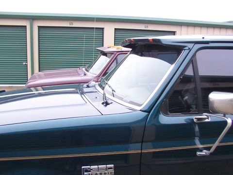 1988 Ford C-350 (Centurion Conversions) - Two 1988 Ford C-350 (Centurion Conversions) trucks are parked side-by-side in front of storage units.