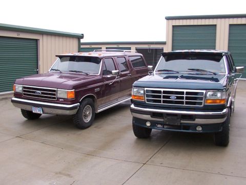 1988 Ford C-350 (Centurion Conversions) - Two Ford trucks are parked outside storage units on a cloudy day.