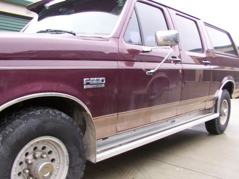 1988 Ford C-350 (Centurion Conversions) - Maroon Ford F-350 extended cab pickup truck with tan lower body trim and running boards, viewed from the side.