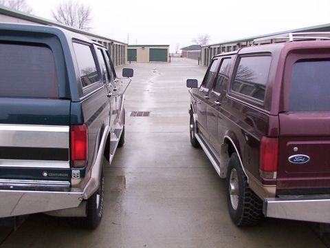 1988 Ford C-350 (Centurion Conversions) - Two Ford SUVs, possibly Centurion conversions, are parked facing each other in a storage unit lot.