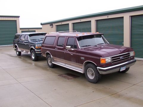 1988 Ford C-350 (Centurion Conversions) - Two Ford SUV conversions are parked side-by-side in front of storage unit doors.