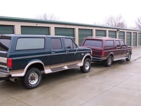 1988 Ford C-350 (Centurion Conversions) - Two Ford SUVs are parked in front of a row of storage unit doors.