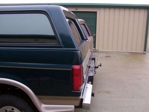 1988 Ford C-350 (Centurion Conversions) - Two SUVs with camper shells are parked side-by-side in front of storage units.