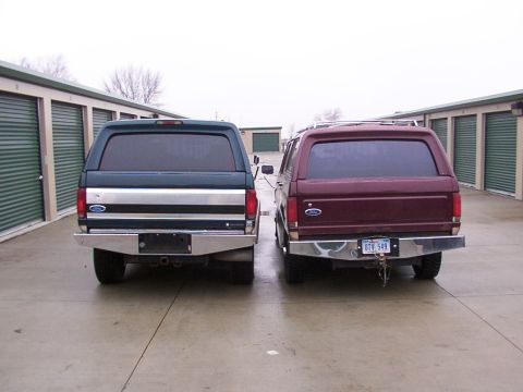 1988 Ford C-350 (Centurion Conversions) - Two SUVs with camper shells are parked in front of storage units.