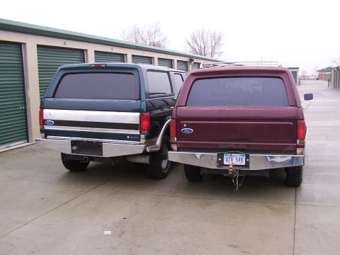1988 Ford C-350 (Centurion Conversions) - Two Ford trucks, a dark green and a maroon model, are parked side-by-side in front of storage units.
