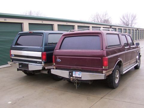 1988 Ford C-350 (Centurion Conversions) - Two Ford SUVs with camper shells are parked side-by-side in front of storage units.