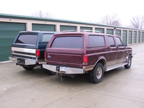 1988 Ford C-350 (Centurion Conversions) - Two Ford Bronco Centurion conversions are parked side-by-side in front of a row of storage units.