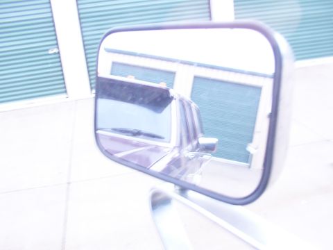 1988 Ford C-350 (Centurion Conversions) - Side mirror reflection shows the rear of a 1988 Ford C-350 (Centurion Conversions) truck, including its windshield wiper and rear window.