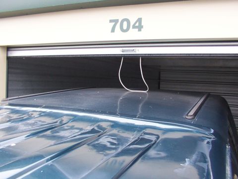 1988 Ford C-350 (Centurion Conversions) - The top of a dark blue SUV is visible, with a white cord hanging from the garage door above.