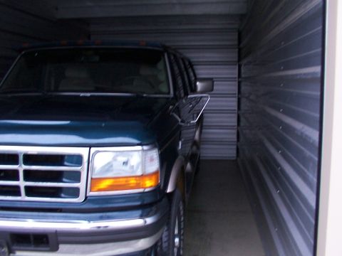 1988 Ford C-350 (Centurion Conversions) - This dark blue Ford F-Series truck is parked inside a storage unit.