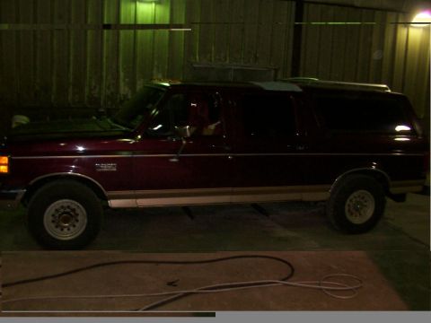 1988 Ford C-350 (Centurion Conversions) - Maroon Ford Bronco with tan trim is parked inside a garage.