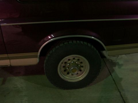 1988 Ford C-350 (Centurion Conversions) - Close-up of a vehicle's side panel and wheel, with maroon and tan paint and chrome accents.