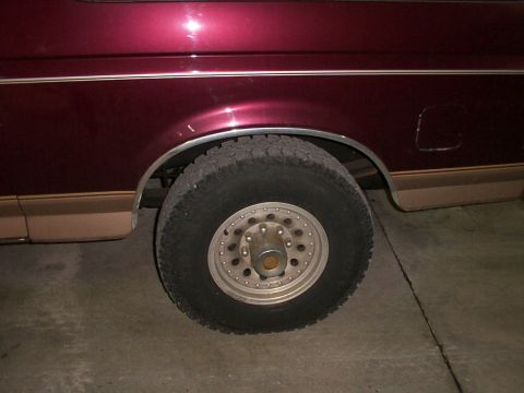 1988 Ford C-350 (Centurion Conversions) - Close-up view of the rear wheel and fender of a maroon vehicle, showing the tire and rim.