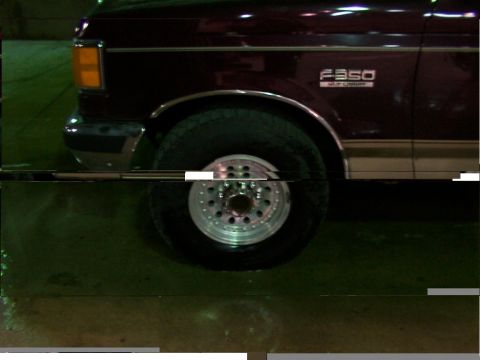 1988 Ford C-350 (Centurion Conversions) - The front wheel and fender of a maroon 1988 Ford F-350 truck are visible in this close-up shot.