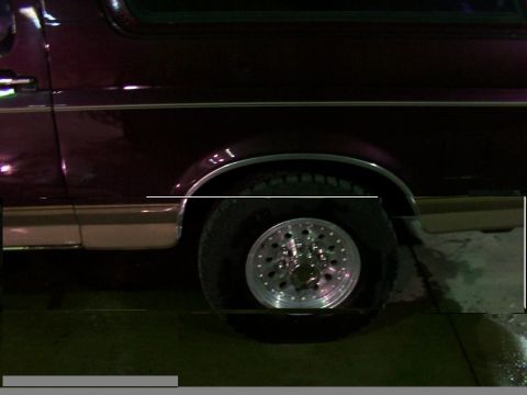 1988 Ford C-350 (Centurion Conversions) - A maroon and tan van is seen from the side, focusing on the rear wheel and fender area.