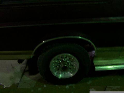 1988 Ford C-350 (Centurion Conversions) - The side profile of a vehicle shows a wheel with a distinctive rim and a chrome accent along the lower body.