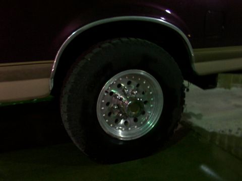 1988 Ford C-350 (Centurion Conversions) - Close-up of a vehicle's wheel and fender, showing the tire and custom rim.