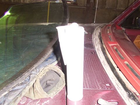 1988 Ford C-350 (Centurion Conversions) - Close-up of a windshield wiper fluid reservoir on a maroon vehicle's cowl.