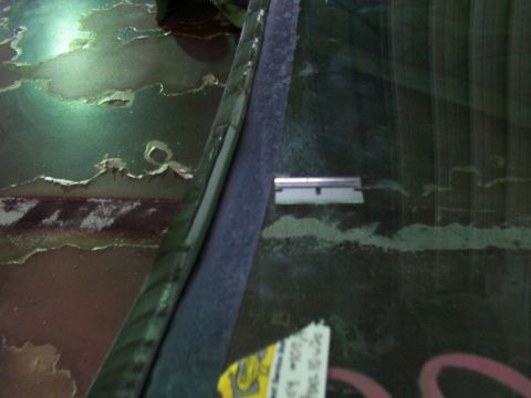 1988 Ford C-350 (Centurion Conversions) - The edge of a windshield shows a razor blade, with damaged paint on the vehicle's body.