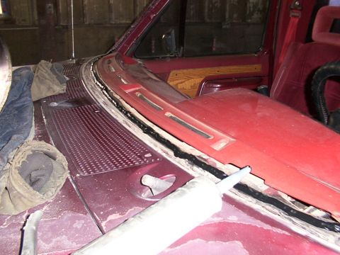 1988 Ford C-350 (Centurion Conversions) - Sealant is applied to the windshield frame of a maroon vehicle during a repair.