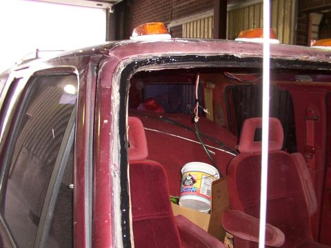 1988 Ford C-350 (Centurion Conversions) - The interior of a vehicle shows red velour seats and a bucket with labels, with the windshield area exposed.