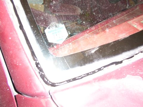 1988 Ford C-350 (Centurion Conversions) - The photo shows a close-up of the windshield seal and interior of a vehicle, with a sticker on the glass.