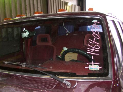 1988 Ford C-350 (Centurion Conversions) - The interior of a maroon truck is visible, including the seats, steering wheel, and writing on the windshield.