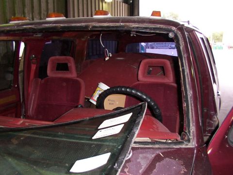 1988 Ford C-350 (Centurion Conversions) - Interior view of a 1988 Ford C-350 (Centurion Conversions) with a broken windshield and maroon upholstery.