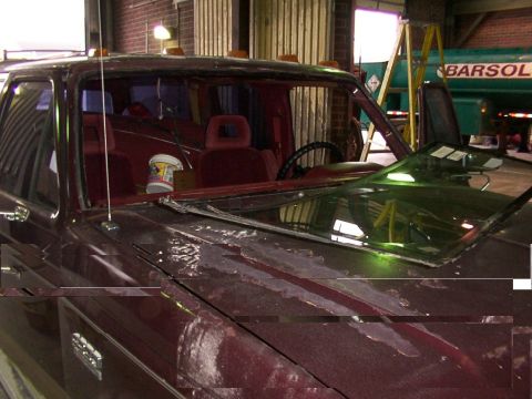 1988 Ford C-350 (Centurion Conversions) - The interior of a maroon truck shows a damaged windshield and peeling paint on the hood, consistent with a 1988 Ford C-350 (Centurion Conve…