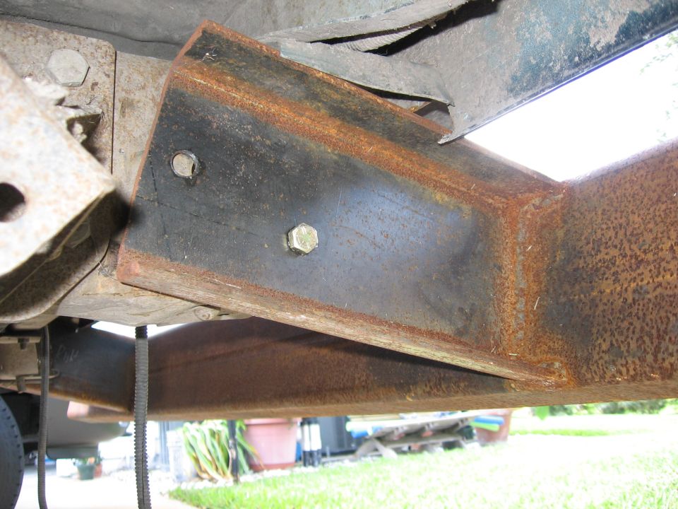 Close-up of a rusted metal frame bracket with bolts on a vehicle