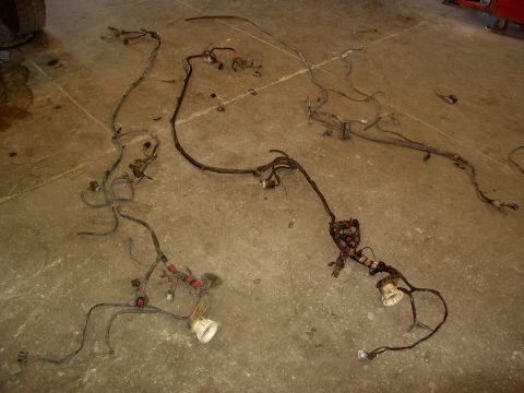 1988 Ford C-350 (Centurion Conversions) - Multiple wiring harnesses are spread across a concrete surface, likely removed from a vehicle's engine compartment and rear sections.