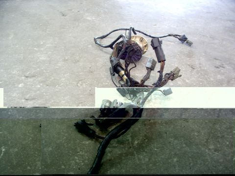 1988 Ford C-350 (Centurion Conversions) - A disassembled wiring harness lies on a concrete floor, showing various connectors and a central beige component.