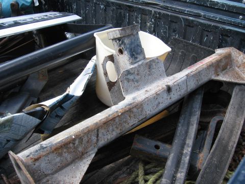 1974 Ford F-100 - Various metal parts, including Ford tailgate trim, are stored in the bed of a truck.