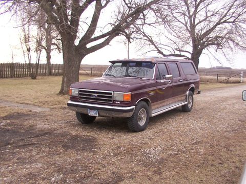 1988 Ford C-350 (Centurion Conversions) - Maroon SUV with a chrome bumper and trim, parked on a gravel driveway under bare trees.