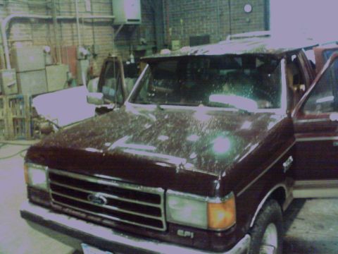 1988 Ford C-350 (Centurion Conversions) - Front view of a maroon Ford F-Series truck, showing its grille and headlights. Another vehicle is partially visible to the left.