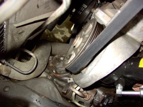 1988 Ford C-350 (Centurion Conversions) - Close-up view of engine components, including a serpentine belt and pulleys, with some fluid stains visible.