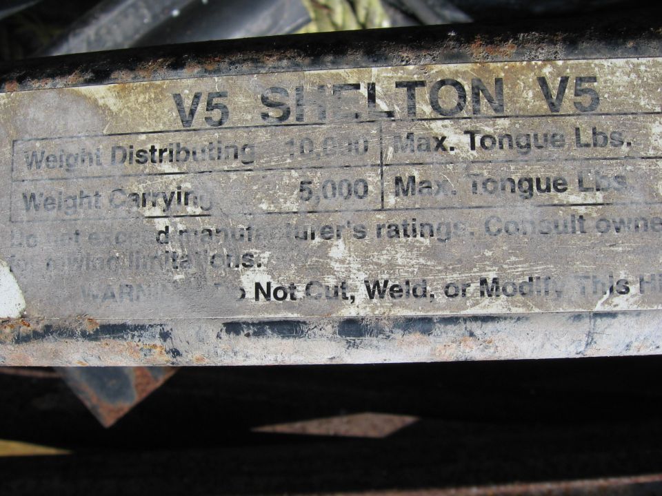 Metal plate with text: V5 SHELTON V5, Weight Distributing 10,000, Max. Tongue Lbs., Weight Carrying 5,000, Max. Tongue Lbs., Do not exceed manufacturer's ratings. Consult owner's manual limits. WARNING: Do Not Cut, Weld, or Modify. This Hi