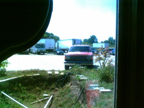 1988 Ford C-350 (Centurion Conversions) - A red pickup truck is parked in a lot with several other vehicles, including semi-trucks and cars.