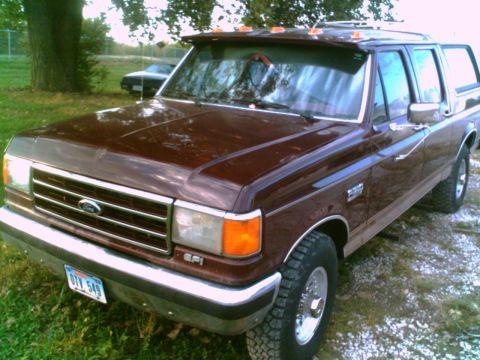 1988 Ford C-350 (Centurion Conversions) - This maroon Ford truck, likely a 1987 model based on its body style, is shown from a 3/4 front angle with a camper shell installed.