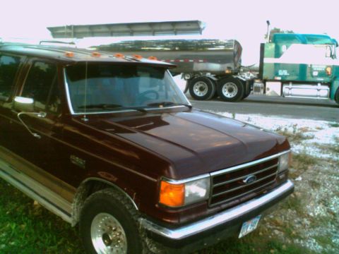 1988 Ford C-350 (Centurion Conversions) - Maroon Ford F-Series truck parked next to two semi-trucks on a roadside.