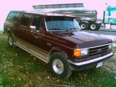 1988 Ford C-350 (Centurion Conversions) - This maroon Ford Centurion conversion SUV is parked on a grassy area with a semi-truck visible in the background.