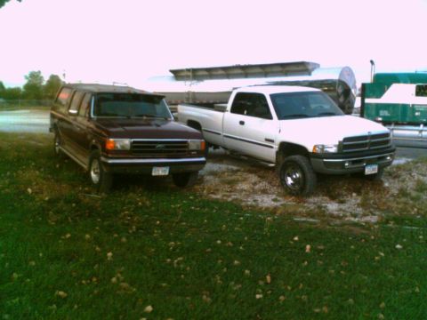 1988 Ford C-350 (Centurion Conversions) - A maroon van with a camper shell is parked next to a white pickup truck.