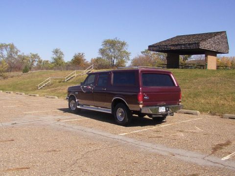 1988 Ford C-350 (Centurion Conversions) - Maroon SUV parked in a lot with a picnic shelter in the background.